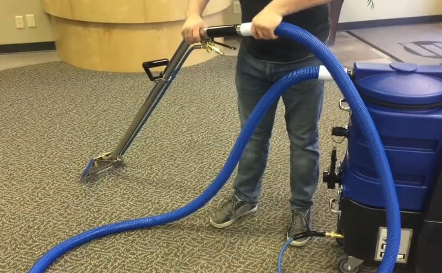 Person using a Flood master carpet cleaning machine on a carpeted floor
