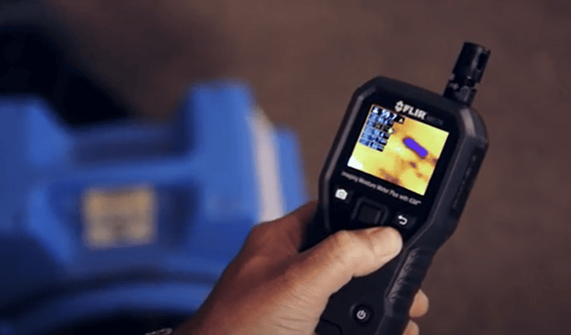 Hand holding a FLIR_MR176 thermal imaging device with a blurred background