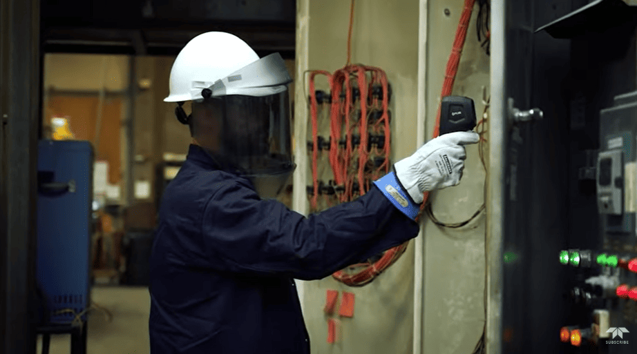 Person in a workshop wearing a hard hat and safety goggles, working on FLIR TG268