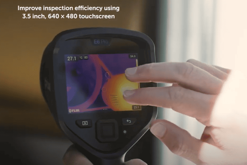 Flir e6 Thermographic camera with a hand interacting with its touchscreen, used for inspection efficiency.