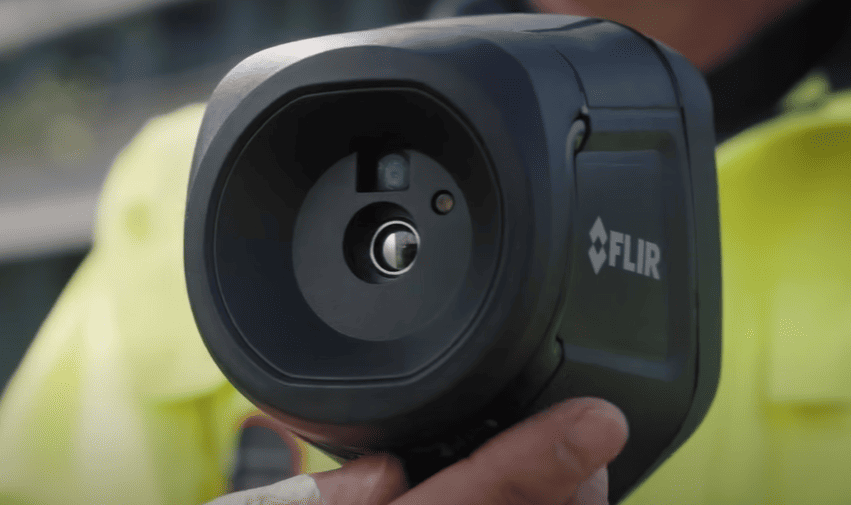 Flir thermal imaging camera held by a person with a blurred background