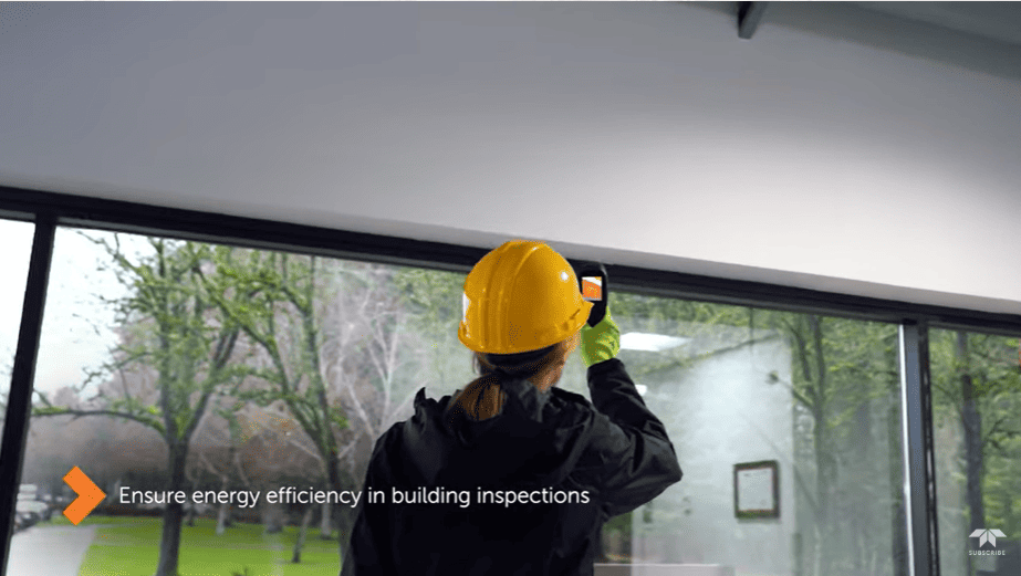Person in a yellow hard hat inspecting a window using a FLIR TG268 with text about energy efficiency.