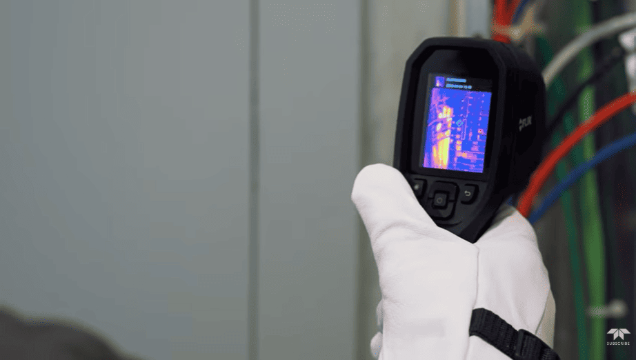 FLIR TG268 Thermal imaging device held by a gloved hand against a neutral background