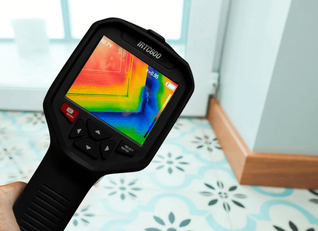 Thermal imaging device showing temperature readings on a tiled floor