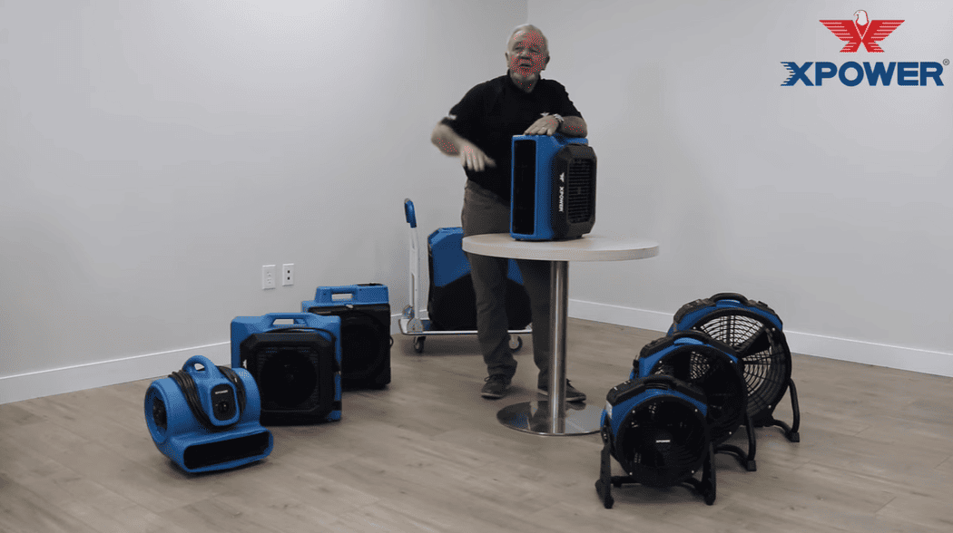 Person demonstrating XPOWER 730a cleaning equipment in a room with white walls and wooden flooring.