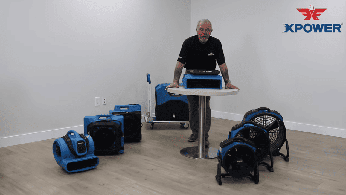 Person demonstrating XPOWER 760am equipment in a room with various air movers and XPOWER logo.