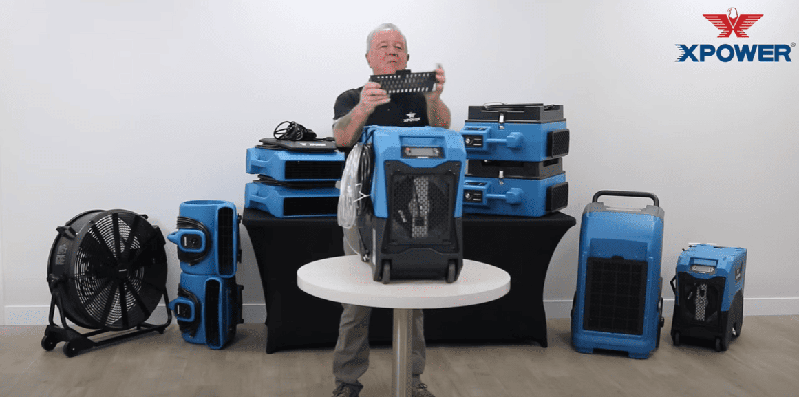 Person demonstrating XPOWER XPOWER_XD125 dehumidifiers and fans in a controlled setting.