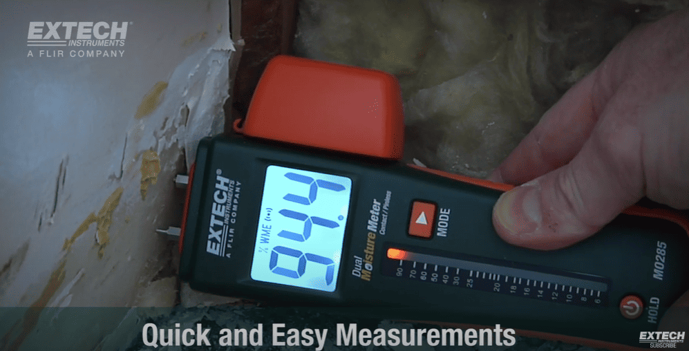 Extechmo60 digital moisture meter being used to measure moisture on a wall