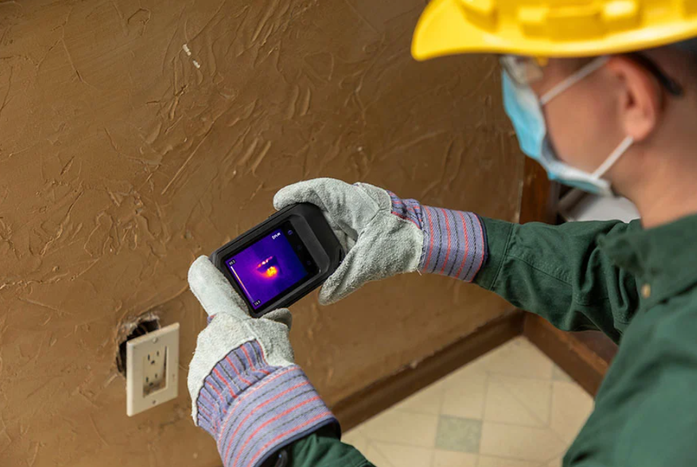 Person using a flir c3 x thermal imaging camera on a wall