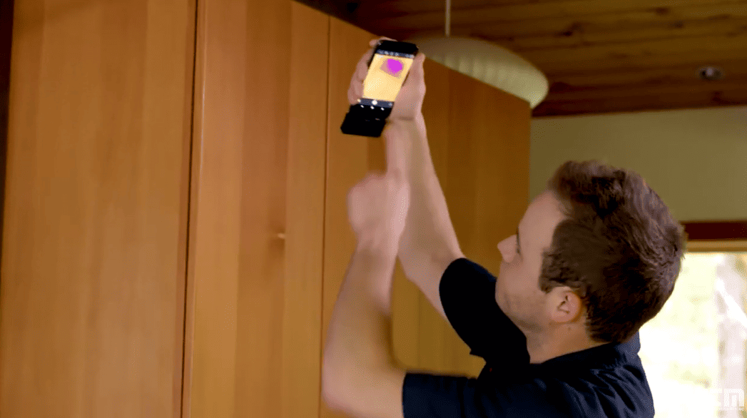 Person using a flir micro usb on android phone to check the temperature of a ceiling light fixture.