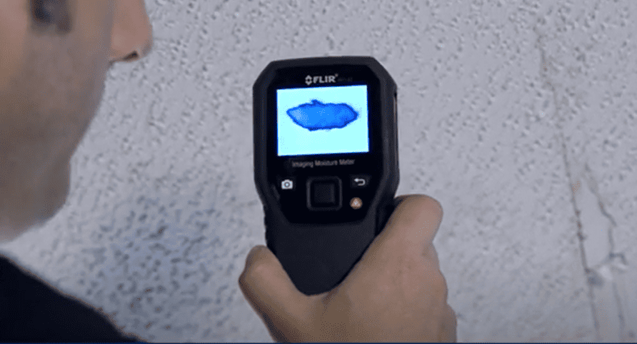 MR160 person using a Flir MR160 thermal imaging device on a textured wall.