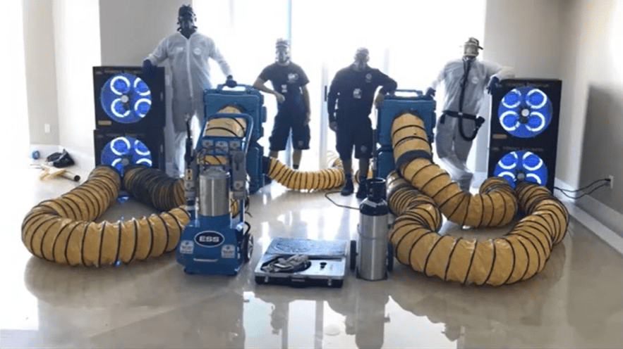 total zone tz 1 ozone generator Commercial cleaning equipment with hoses and workers in protective gear in a room.
