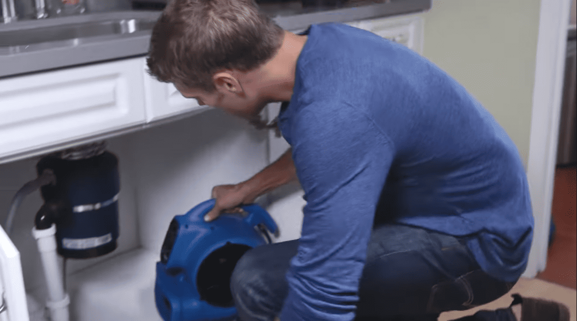 P130A Xpower Person putting an air mover under the kitchen sink
