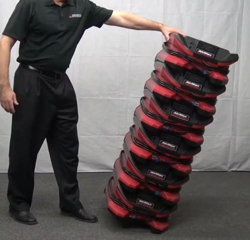 Person stacking red and black phoenix air max on a gray floor with a white wall background