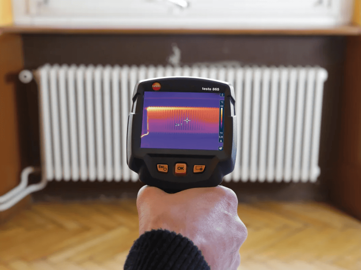 testo 865s Thermal imaging device pointing at a radiator in a room.