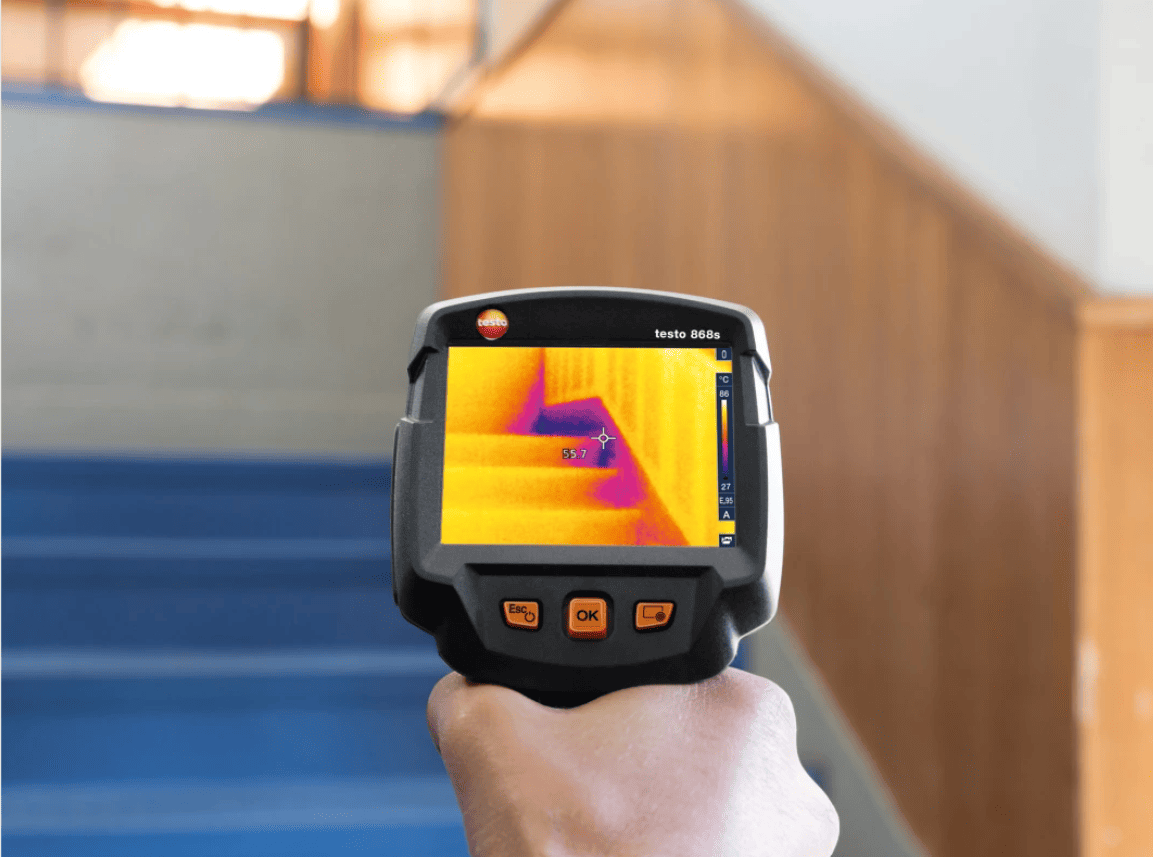 testo 868s Thermographic camera being held with thermal imaging on a wall
