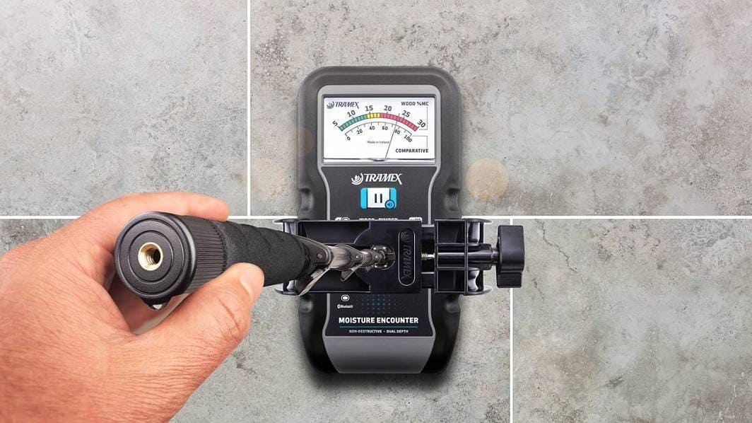 Hand using a moisture meter Tramex ME5 on a tiled wall