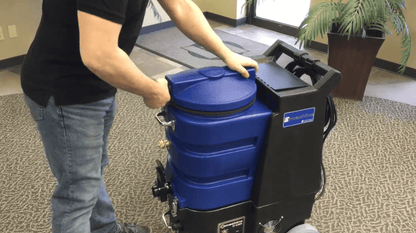 Person pushing a large blue and black E1200 Hard Surface Cleaner in an indoor setting