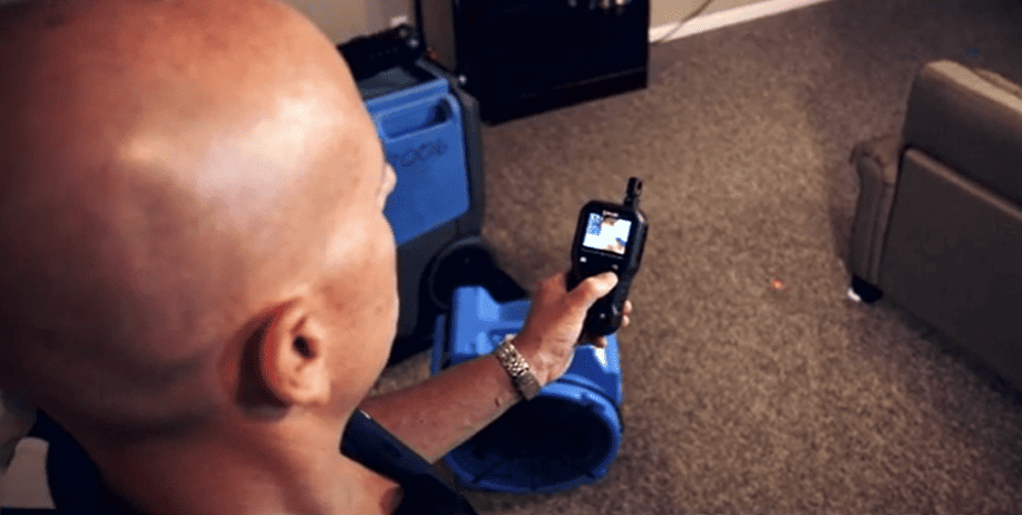 Person holding a FLIR_MR176 in an indoor setting with furniture 