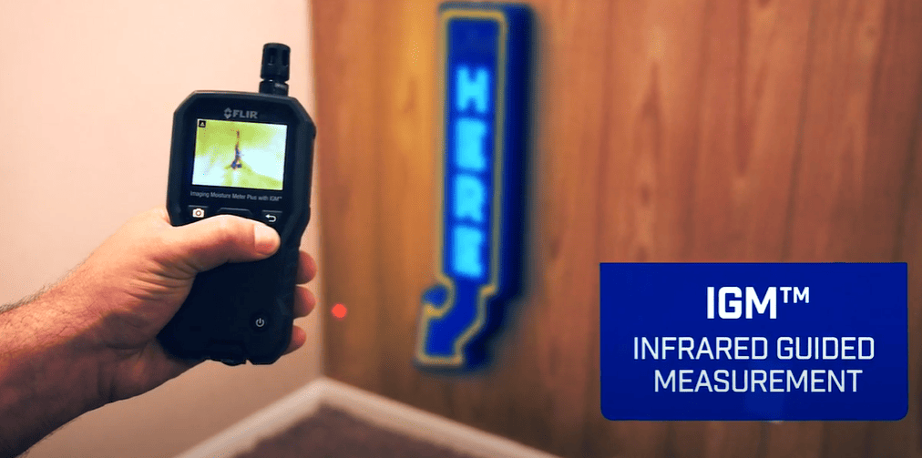 MR176 Hand holding an infrared measurement device with IGM logo on a wooden wall background