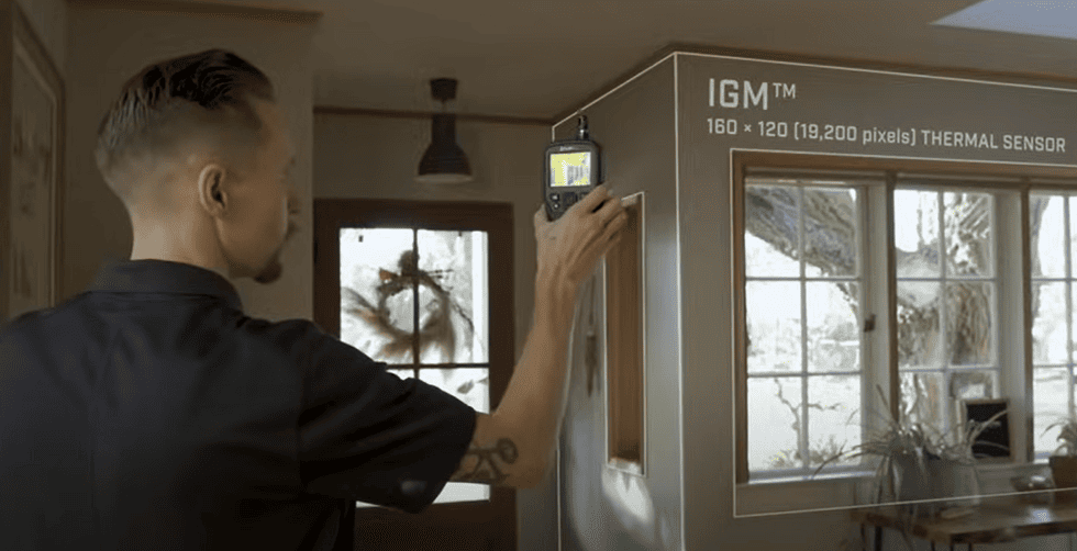 MR277 Person installing a device labeled 'IGM' in a room with large windows.