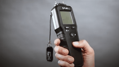 hand holding a Moisture Meter MR55  against a gray background