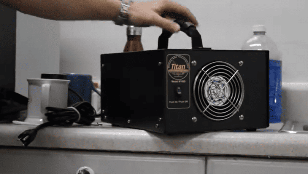 Black Generator Titan 1000 labeled 'Titan' on a kitchen counter with a hand holding it.