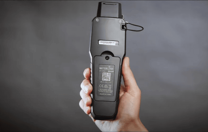 Hand holding a black MR55 with 'METERLINk' branding against a gray background