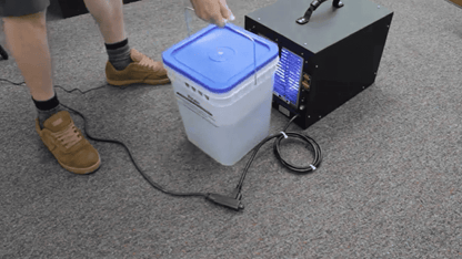 Person using a International Ozone Titan 2000 and a white Titan Maximizer with a blue lid on a gray floor.