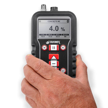 Hand holding a digital tramex concrete x5 concrete moisture content measurement on a white background