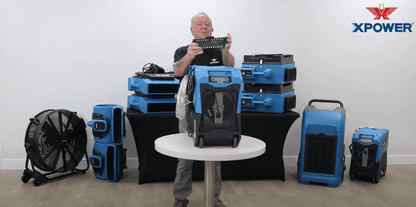 Person demonstrating XPOWER XPOWER_XD125 dehumidifiers and fans in a controlled setting.
