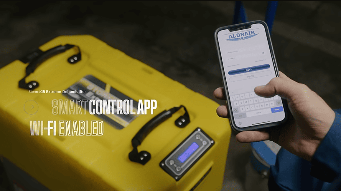 Person holding a smartphone with a control app displayed next to a alorair storm lgr extreme dehumidifier.