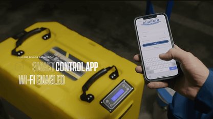 Person holding a smartphone with a control app displayed next to a alorair storm lgr extreme dehumidifier.