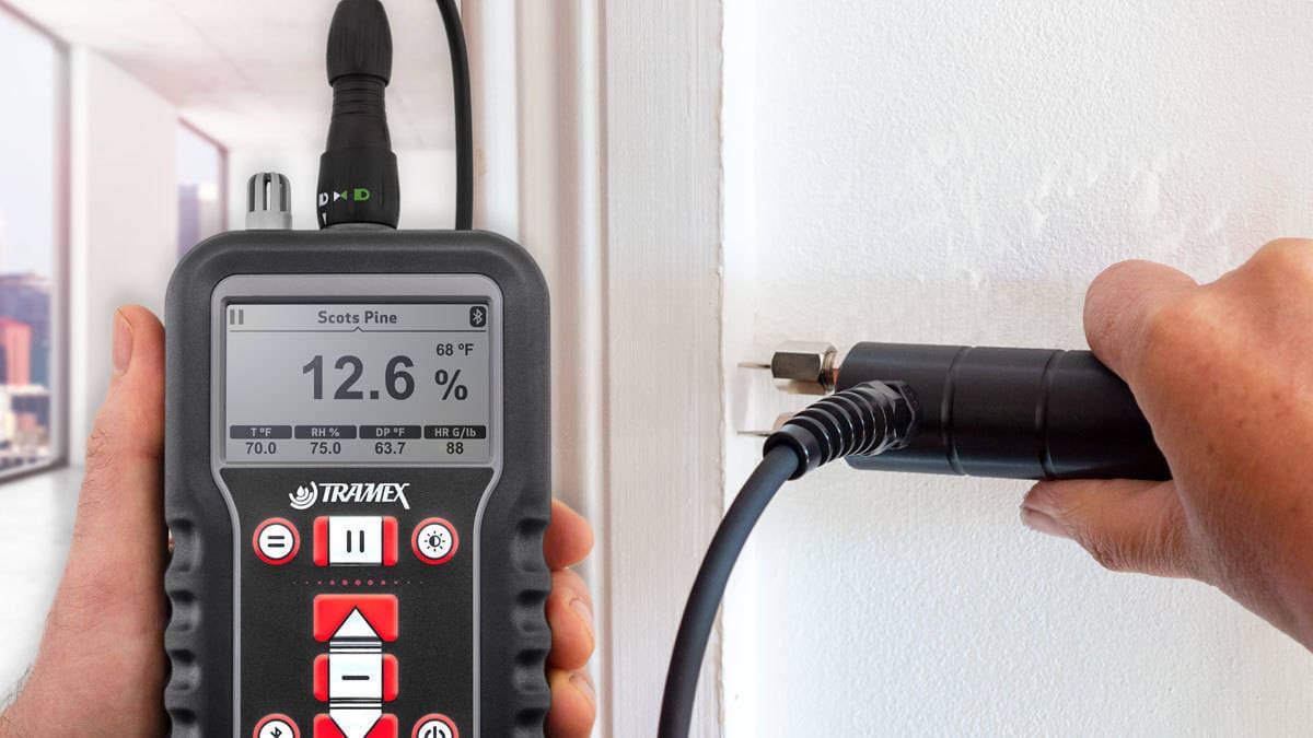 Person using a TRAMAX x5 moisture meter to check the humidity level of a wall.