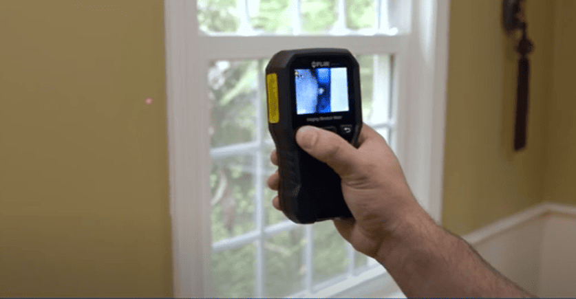 Flir MR160 hand holding a thermal imaging device in front of a window