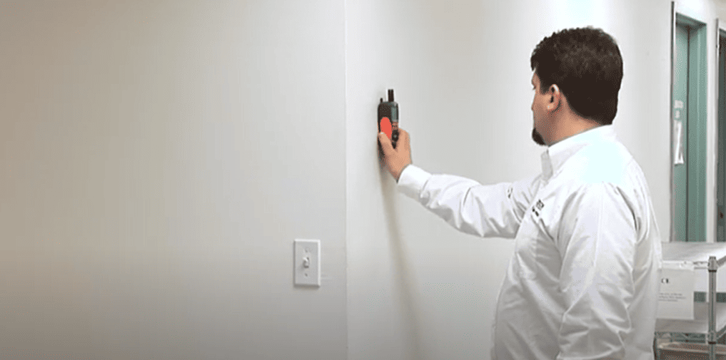 Person in a white polo using a  mo290 device on a wall