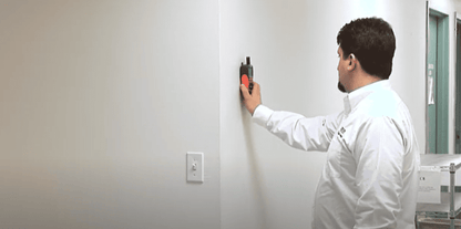 Person in a white polo using a  mo290 device on a wall