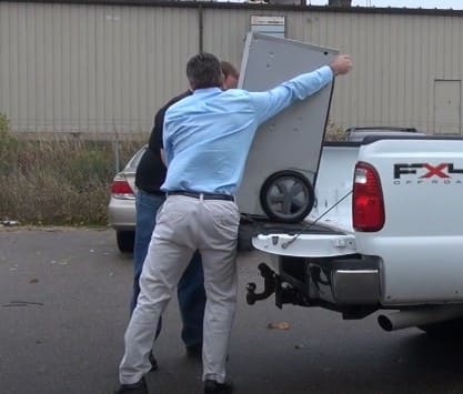 Two men loading a phoenix 250 max into the back of a white truck 