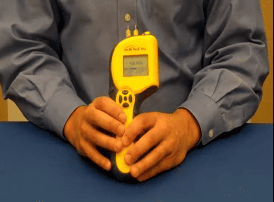 Person holding delmhorst techcheck_plus on a blue surface