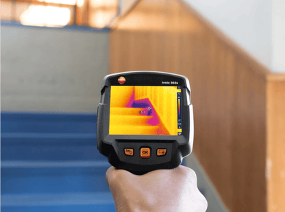 testo 868s Thermographic camera being held with thermal imaging on a wall