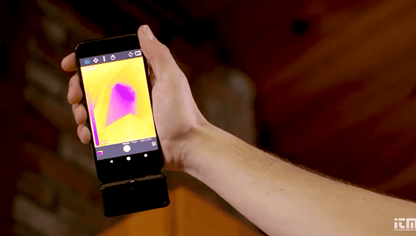 Hand holding a smartphone displaying a  usb c thermal camera app on a blurred background